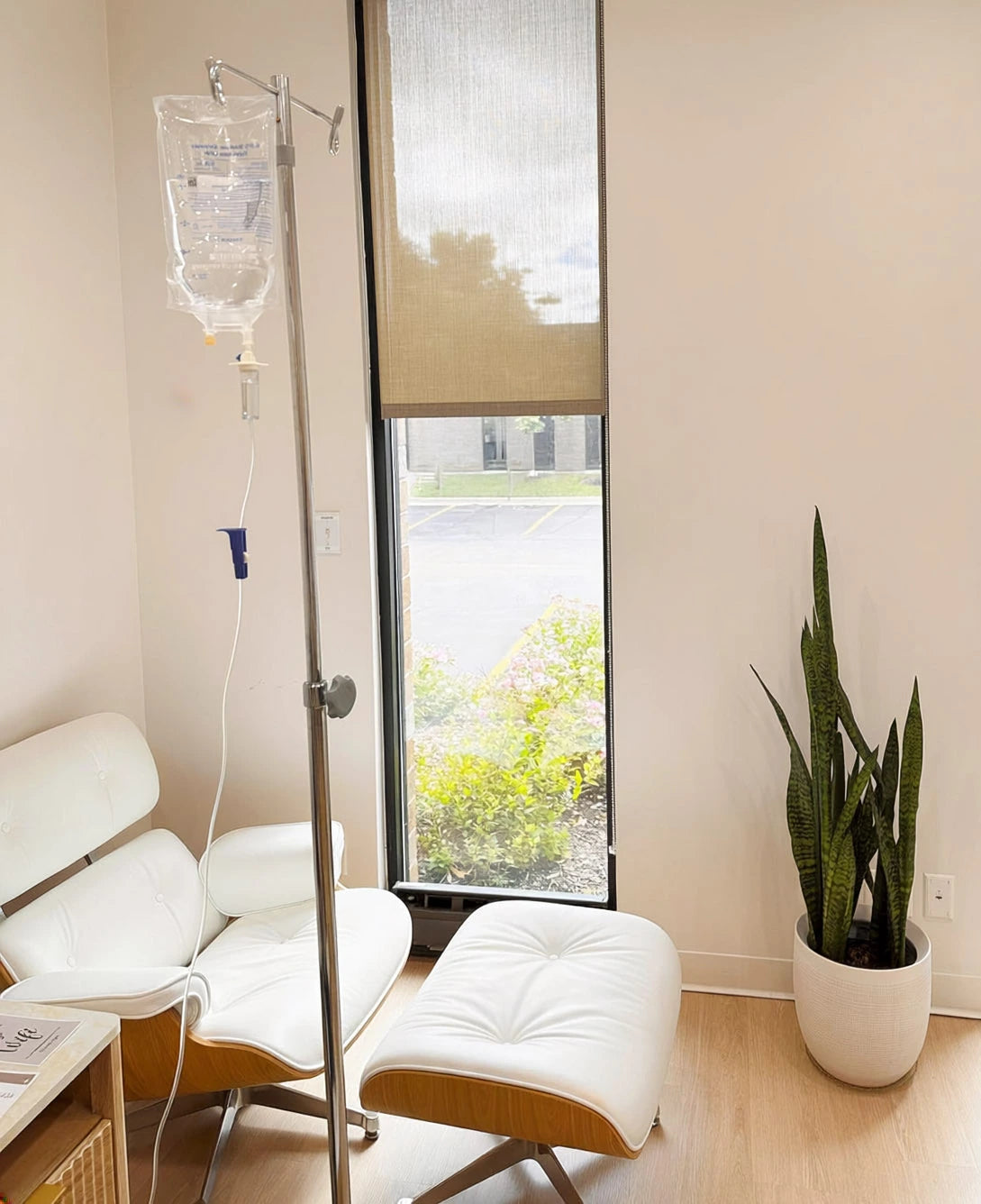 Shine IV therapy lounge with a white treatment chair, ottoman, and infusion stand by a sunlit window